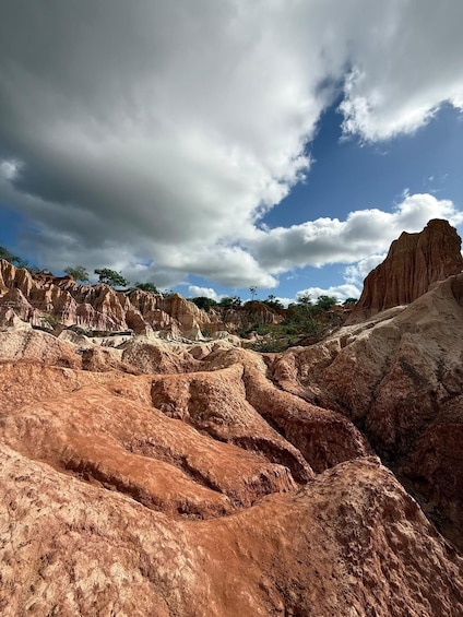 A rugged landscape with eroded rock formations and a clear sky with clouds. 3
