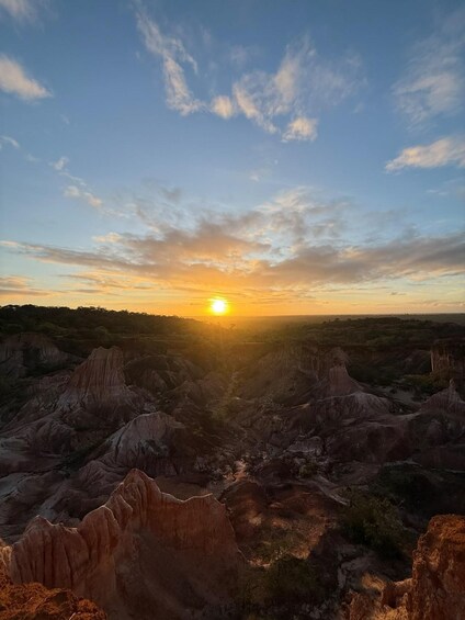 A sunset over a rugged landscape with prominent rock formations. 4