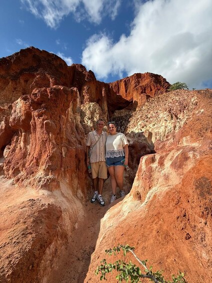 Two people standing in a narrow canyon with red rock formations. 2