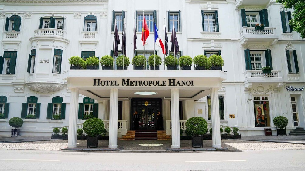 A grand hotel entrance with columns, flags, and a sign reading 'HOTEL METROPOLÉ HANOI.' 3