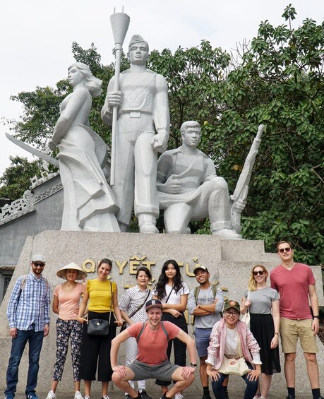 A group of people posing in front of a large stone monument with inscriptions. 2