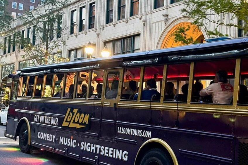 A vintage bus with 'LoZoom' branding, advertising comedy, music, and sightseeing services. 2