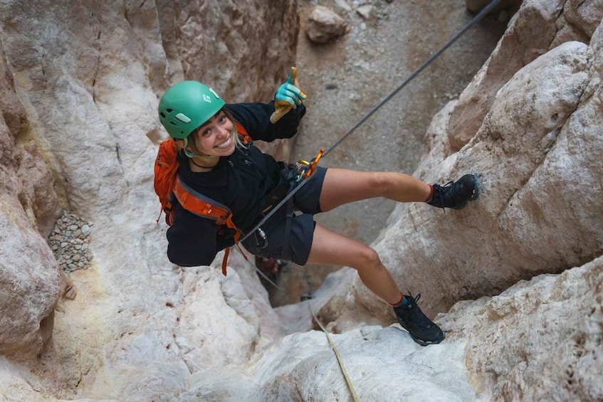 A person rappelling down a rocky cliff. 5
