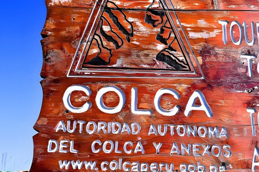 A wooden sign with the text 'COLCA AUTORIDAD AUTONOMA DEL COLCA Y ANEXOS' and a website URL. 3
