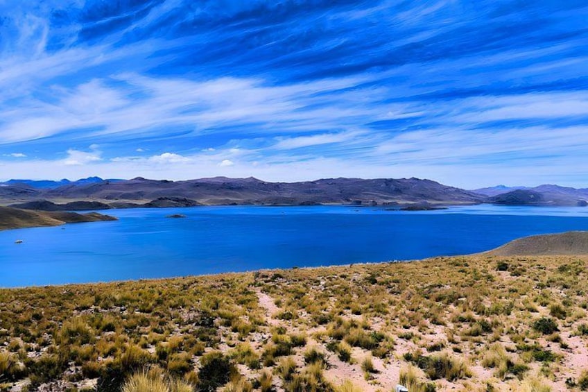 A vast lake surrounded by mountains and sparse vegetation. 5