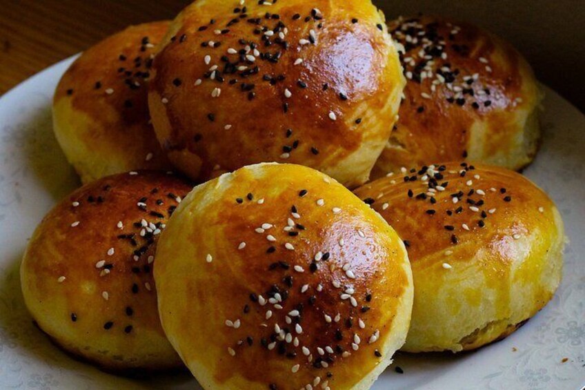 A plate of golden-brown buns with sesame seeds on top. 2