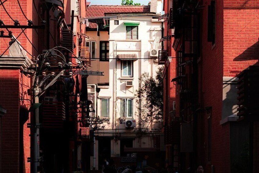 A narrow urban street with red brick buildings, a fire escape, and a visible air conditioning unit. 3