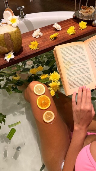 En person som kopplar av i ett badkar med citronskivor och blommor. 2