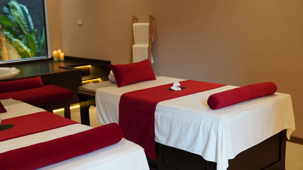 Ett spa-rum med tre behandlingsbäddar, var och en med en röd kudde och en vit handduk. 5