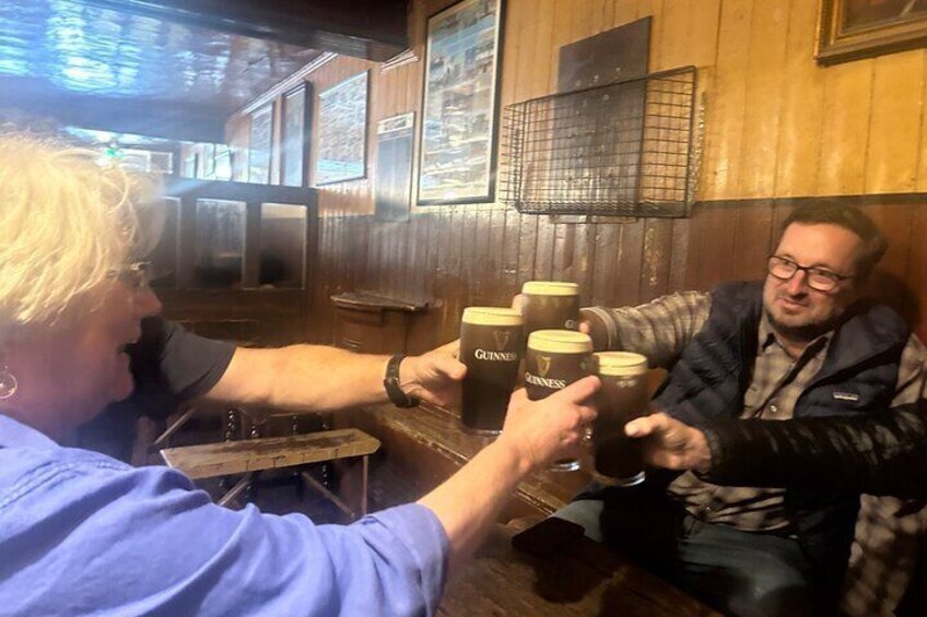 Two people toasting with Guinness beer glasses in a wooden bar. 5