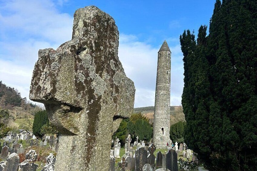 A ruined stone structure with a tall tower, surrounded by trees and a cemetery. 2
