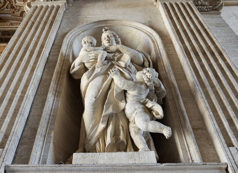 A detailed stone sculpture of a woman holding a child, surrounded by a classical architectural structure. 4