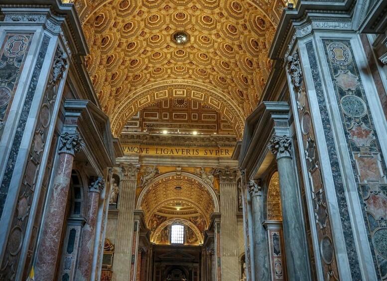 An ornate interior with a golden ceiling and marble columns. 3