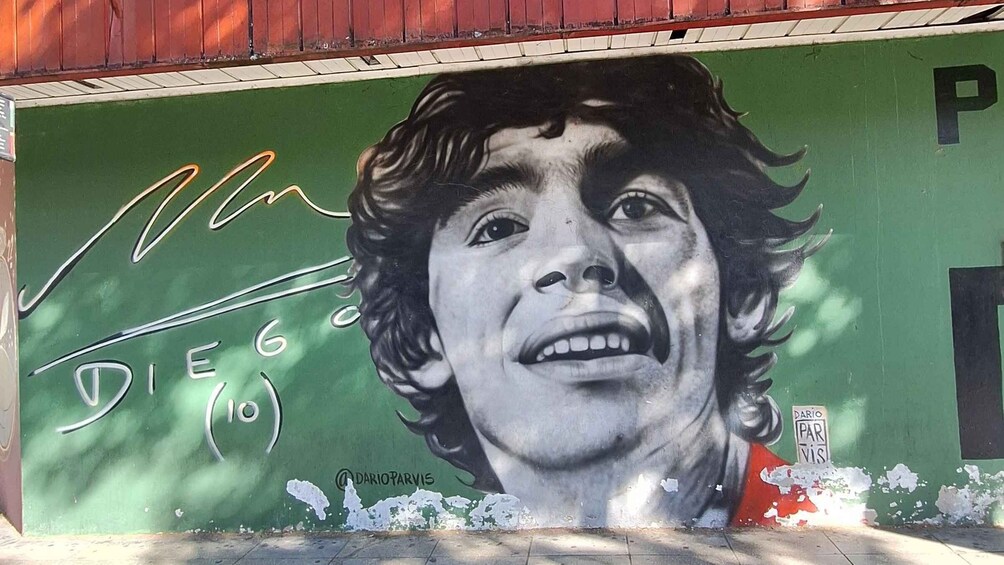 A mural with a person's face, signature, and the text 'Dario' on a green wall. 1