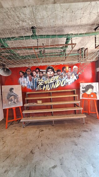 A room with a red wall, a poster of soccer players, and two easels with paintings. 4