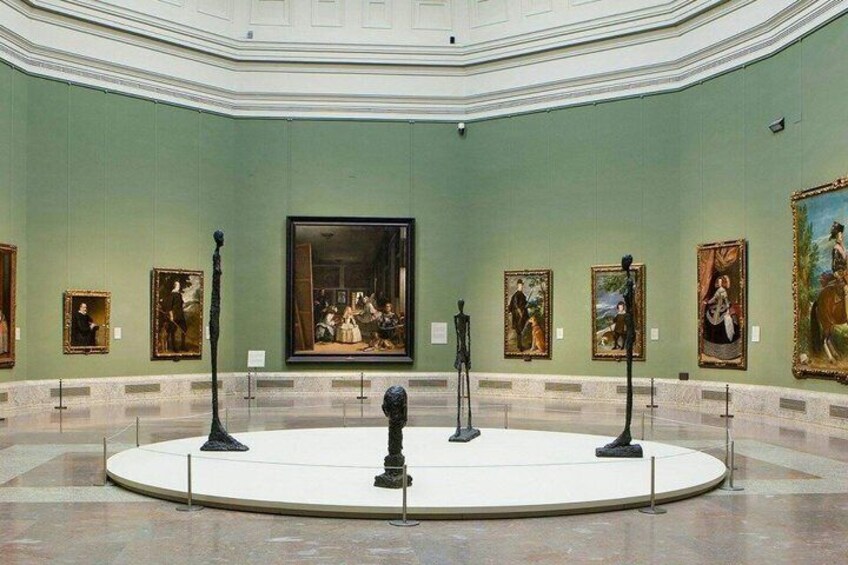 A museum interior with classical paintings and sculptures on display. 4