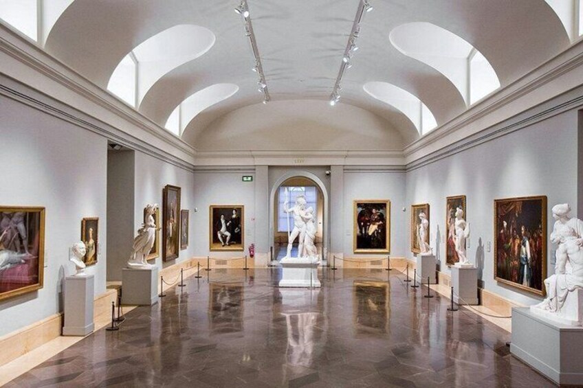 An art gallery with classical sculptures and paintings on display. 2