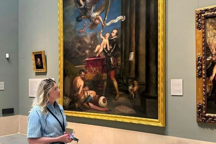 A person observing a large classical painting in a museum. 5