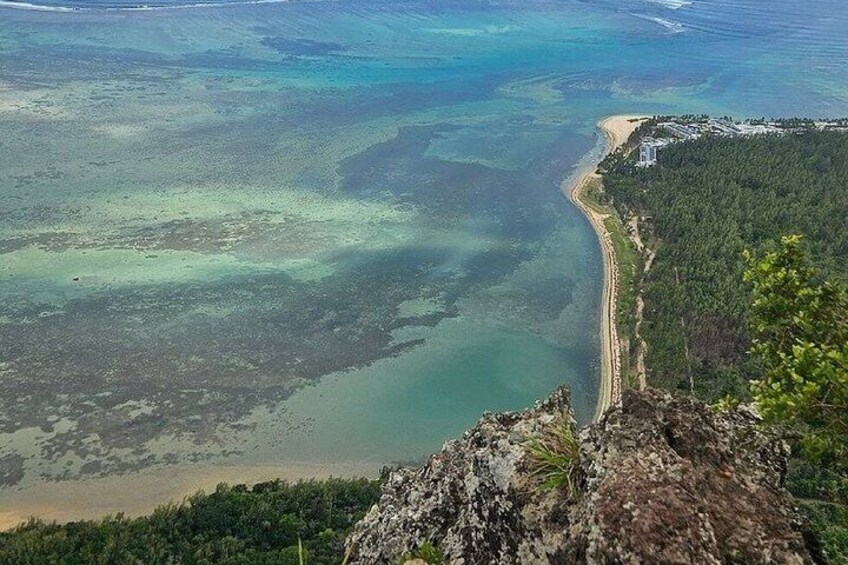 A coastal landscape with a beach, clear waters, and a forested area. 3
