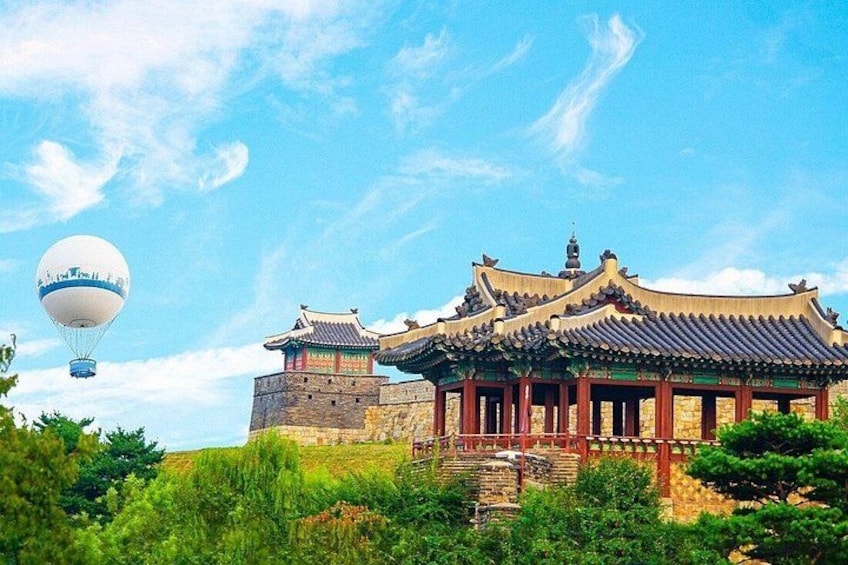 A traditional Chinese building with a red roof and a stone tower in the background. 1