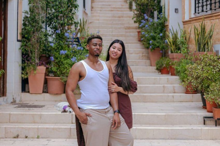 A staircase with potted plants, a person in a white tank top, and another in a maroon top. 3