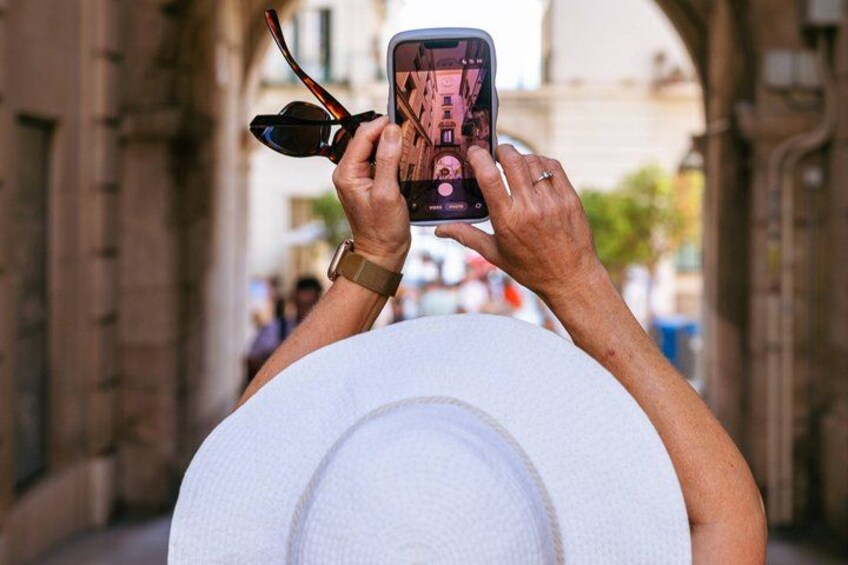 A person holding a smartphone, taking a photo through a white hat. 2