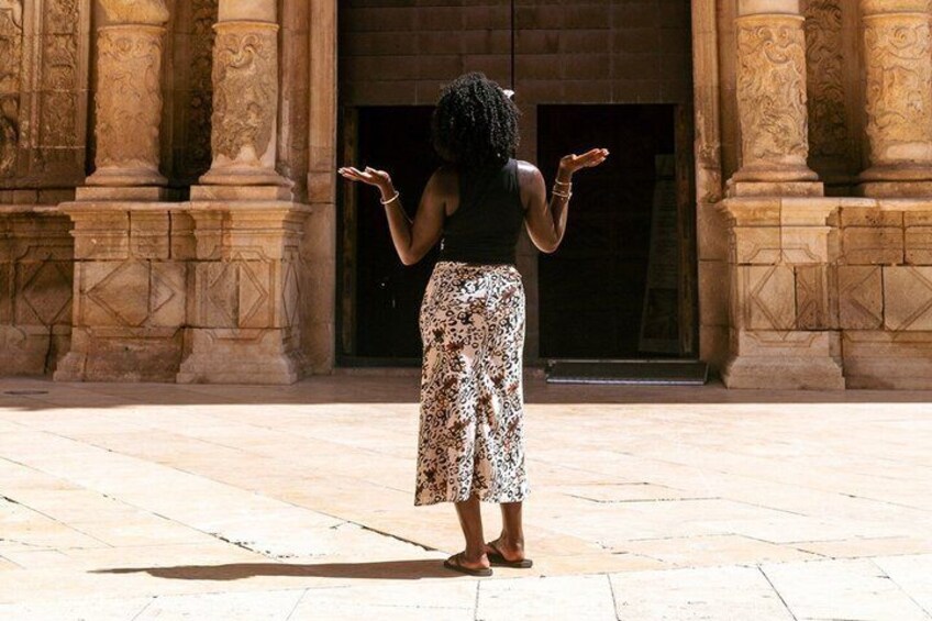 A person standing in front of a building with large columns and a door. 4