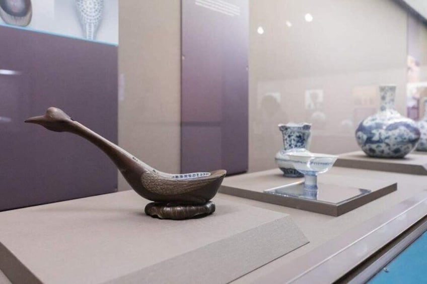 A duck-shaped ceramic object on a display stand. 5