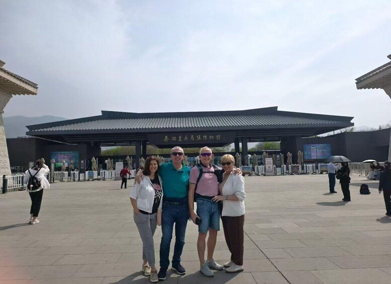 A group of people posing in front of a traditional building with a tiled roof and a sign with Chinese characters. 4