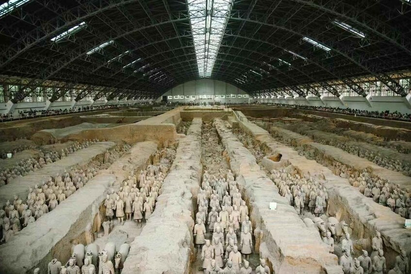 A large indoor archaeological site with rows of terracotta soldiers. 3
