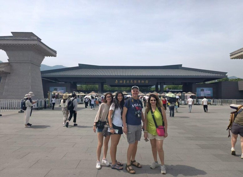 A group of people standing in front of a traditional Korean gate with a modern building in the background. 1