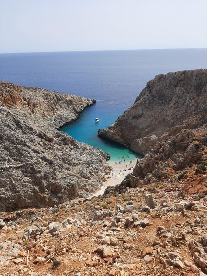 Eine felsige Küstenlinie mit einem kleinen Boot auf dem türkisblauen Meer. 1