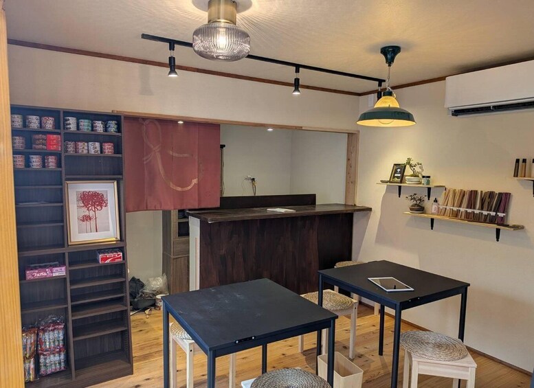A modern interior with a wooden floor, a black table, a white chair, a hanging light fixture, and a shelf with various items. 3