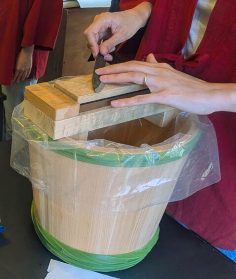 A person assembling a wooden structure, possibly a model or a part of a larger project, with a focus on the hands and the wooden pieces. 2