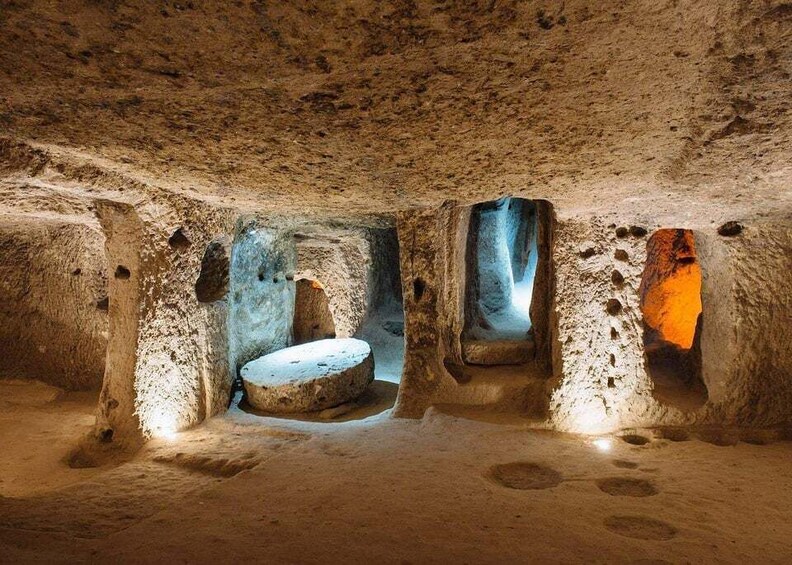 A cave interior with stalactites and stalagmites, illuminated by artificial lighting. 2