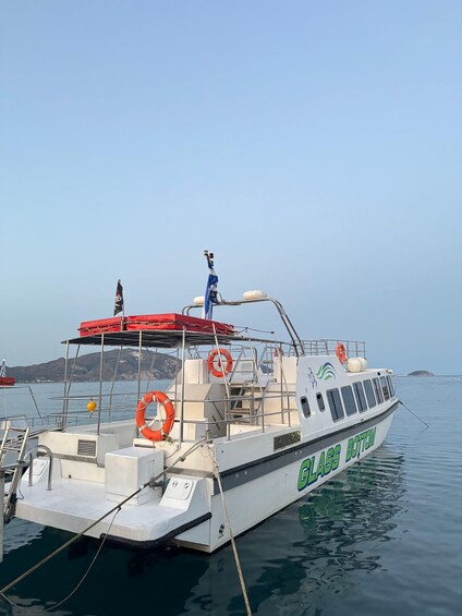 A boat named GLASS BOTTOM docked at a marina with lifebuoys and a flag. 2