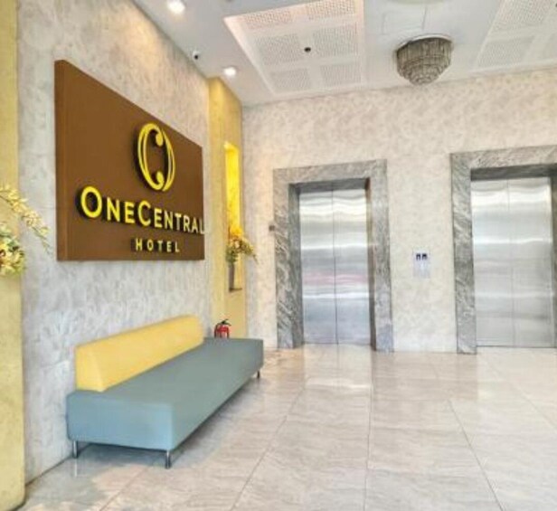 A hotel reception area with a blue sofa, a reception desk, and two elevators. 3