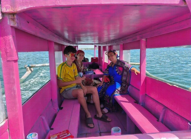 Three people on a pink boat with a water view. 2