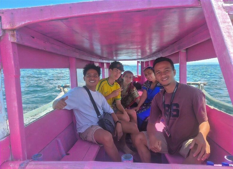 A group of people on a pink boat with the ocean in the background. 3