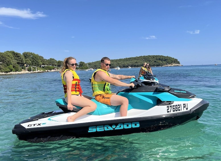 Two people on a jet ski with a clear blue sky and a coastline in the background. 3