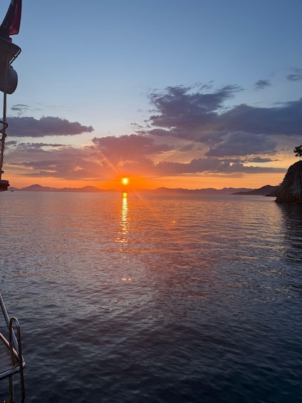 A sunset over calm waters with a boat and a dock on the left. 2