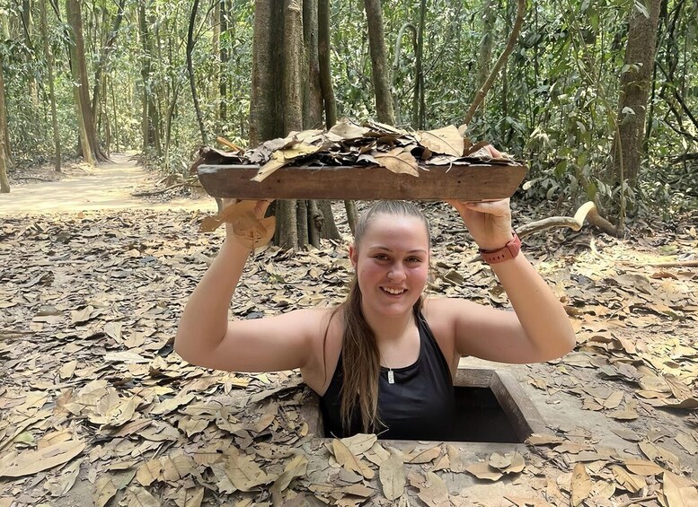 A person holding a tray of leaves above their head in a forest. 5