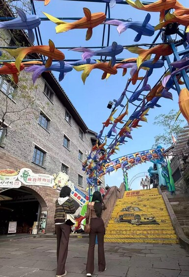 A street decorated with colorful paper streamers, a building with signage, and a staircase leading to a platform. 2