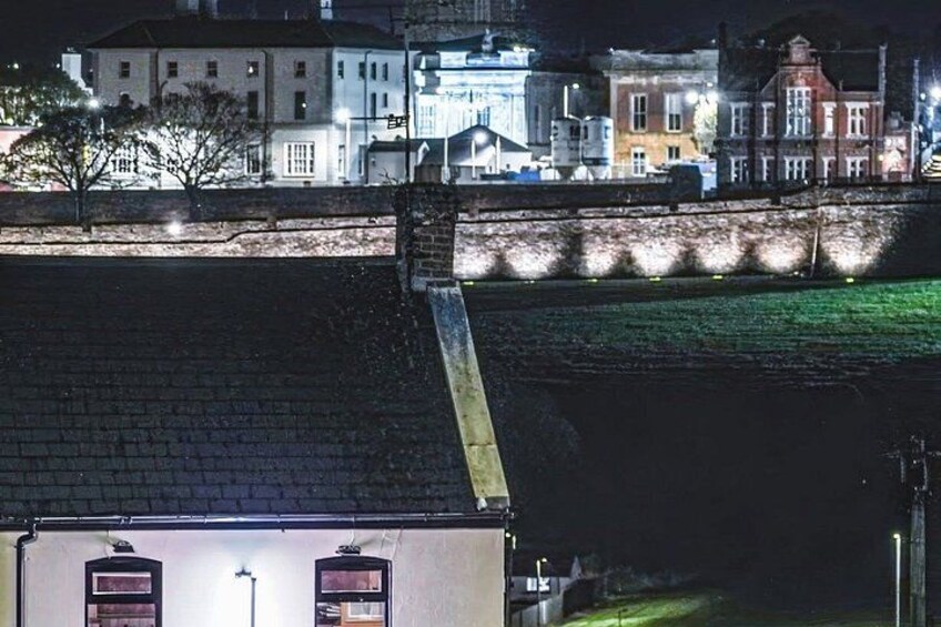 A nighttime cityscape with illuminated buildings, a bridge, and a river. 2