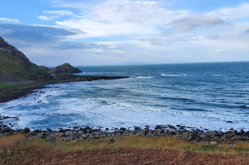 A coastal landscape with rocky cliffs, a rocky shoreline, and the ocean. 2