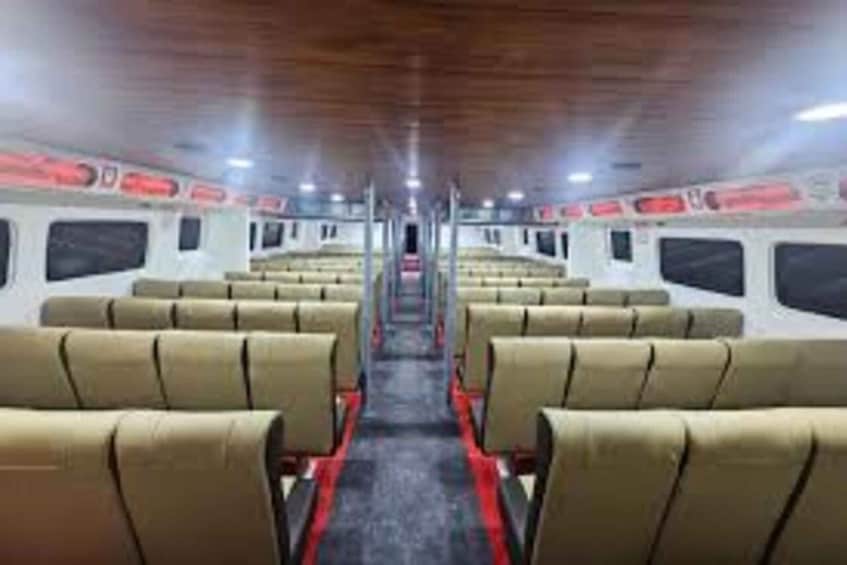 A train interior with rows of beige seats and red carpeting. 5