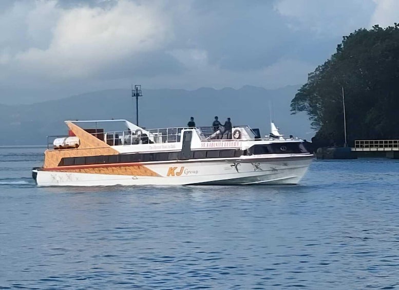 A white and brown boat with 'KJ Cruises' on its side, sailing on calm water with mountains in the background. 4