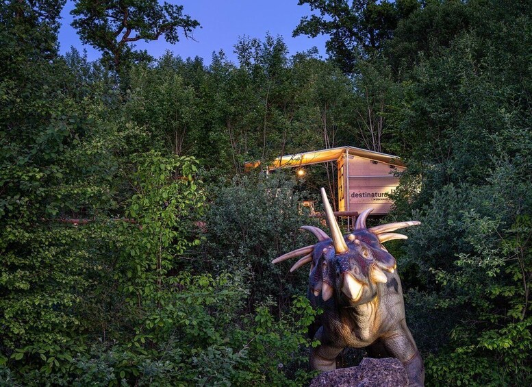 A bronze dinosaur sculpture with a cabin in the background. 5