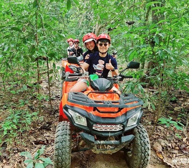 A group of people on an ATV in a forested area. 3