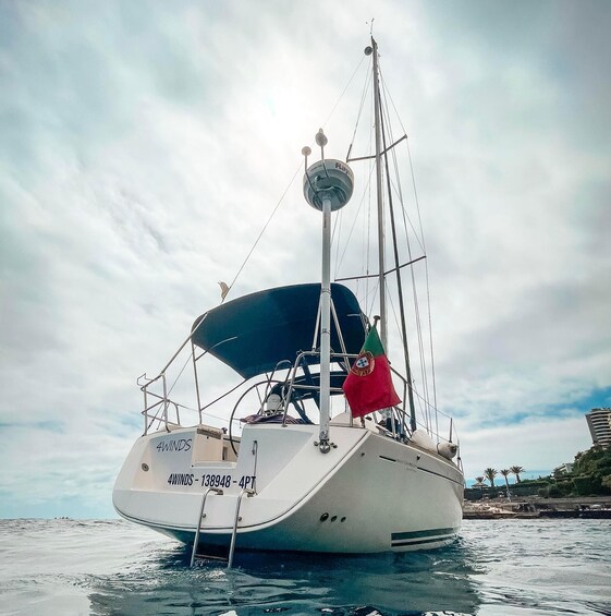 A sailboat named '4Winds' with a Portuguese flag, sailing on calm waters. 1
